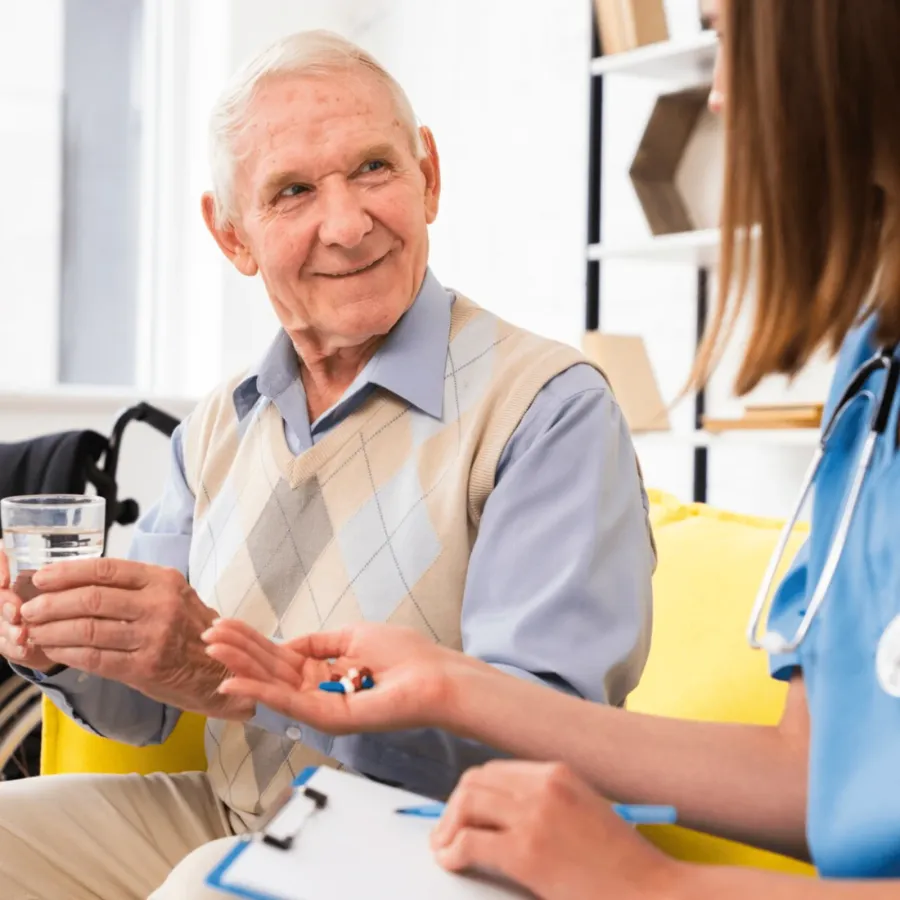 A smiling older man receiving his medication from a hospice nurse